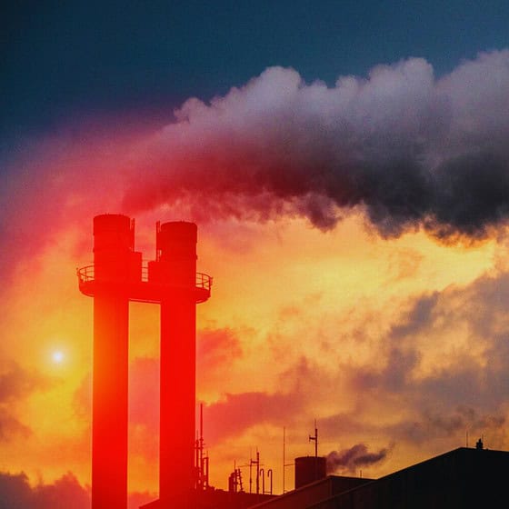 smoke stacks with smoke coming out of the chimney